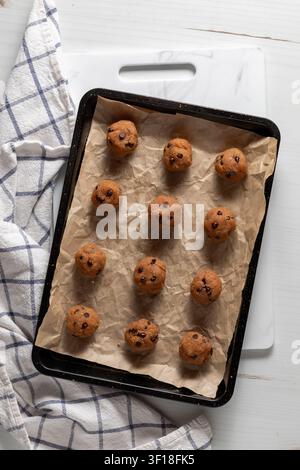 Rows of homemade peanut butter chocolate chip energy balls on baking sheet. Stock Photo