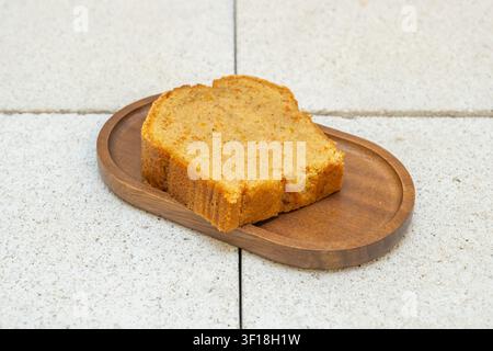 Slice of Moist Orange Pound Cake on an Oval Wooden Serving Board Over Concrete Surface Stock Photo