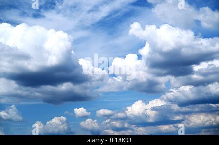 Beautiful blue sky with fluffy white cumulus clouds and light wispy cirrus on a sunny day. Stock Photo