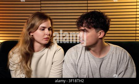 Young couple discussing serious relationship problems while sitting on a couch at home Stock Photo