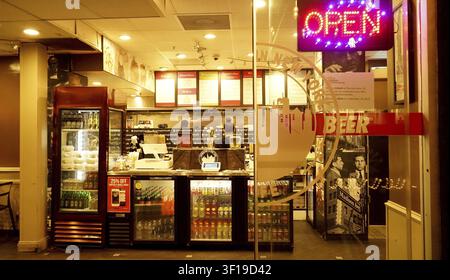 Inside a diner at night showcasing an 'OPEN' neon sign and various beverages, DTLA. Los Angeles, California Stock Photo
