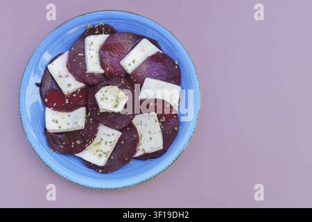 Beetroot and goat cheese salad on a blue plate, garnished with dried herbs, ready for a healthy meal Stock Photo