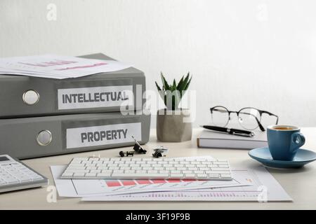Intellectual property. Folders, computer keyboard and stationery on wooden table Stock Photo