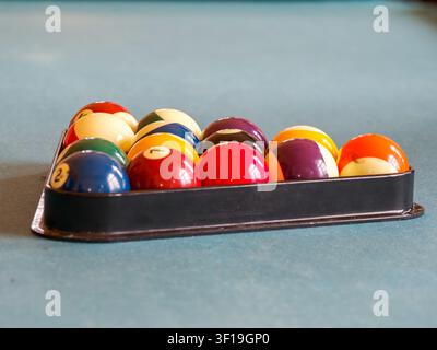 Billiard balls arranged in a triangle rack on a blue felt pool table Stock Photo