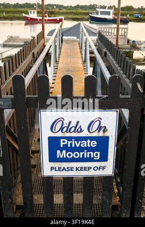 A private mooring sign reading Odds On Private Mooring Please Keep Off on a black wooden gate leading to a gangway at a harbor, Suffolk, England Stock Photo