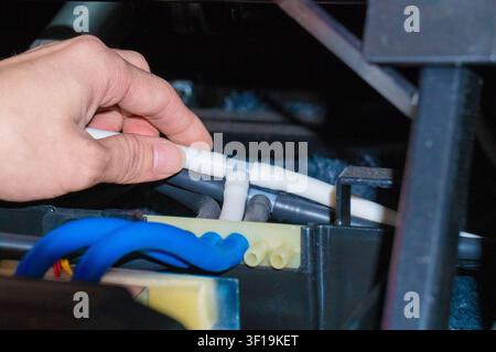 Technical engineer repairing and measuring the electronic motherboard of an electric massage chair with professional tools, hardware repair service. Stock Photo