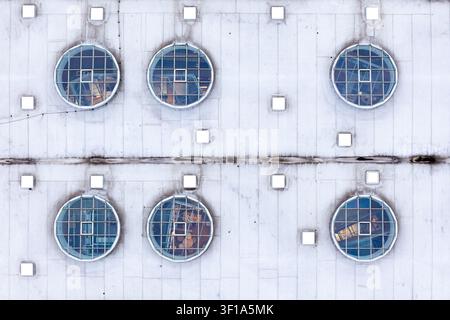 Aerial view of a modern building facade featuring a grid of circular windows and square ventilation panels in Warsaw, Masovian Voivodeship, Poland. Stock Photo