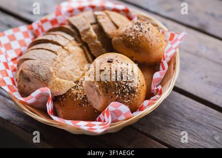 Artisan Sourdough Bread and Seeded Rolls Served in Basket on Wooden Table Stock Photo