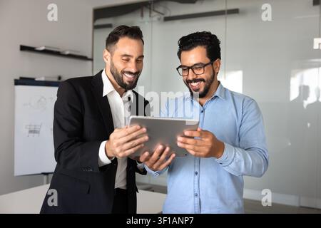 Two smiling colleagues reviewing information, business application on digital tablet Stock Photo