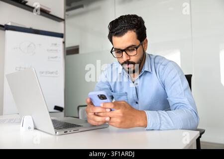 Middle eastern businessman checking smartphone in corporate office Stock Photo