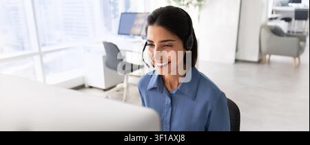 Smiling operator, call center worker working in office using computer Stock Photo