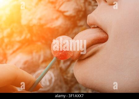 Lollipop tongue candy close up of a person licking a sweet red candy outdoors in warm sunlight Stock Photo