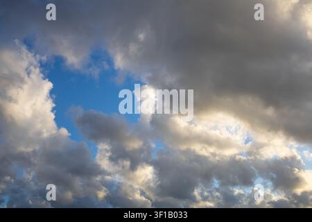 Dramatic storm clouds with bright blue sky opening through white and gray cumulus clouds, natural weather background with copy space Stock Photo