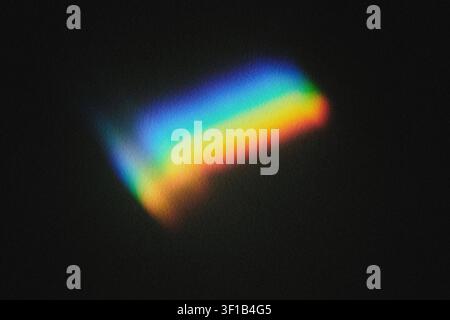 Light refracting through prism creating vivid rainbow spectrum on black surface Stock Photo