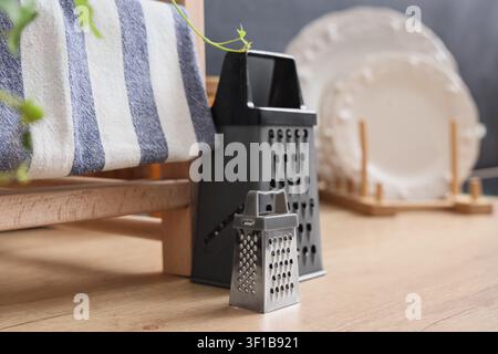 Kitchen scene with two graters a striped towel and white plates on a wooden surface cooking and food preparation, utensil Stock Photo