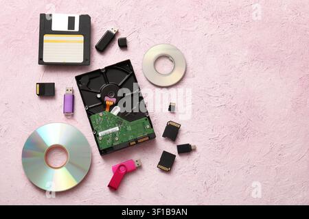 Evolution of data storage devices including floppy disk hard drive usb flash drives and memory cards on a pink background Stock Photo