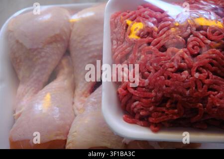 Packaged raw chicken drumsticks and minced beef in plastic trays Stock Photo