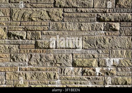 Rough textured natural stone wall with irregular blocks and visible mortar lines. Stock Photo