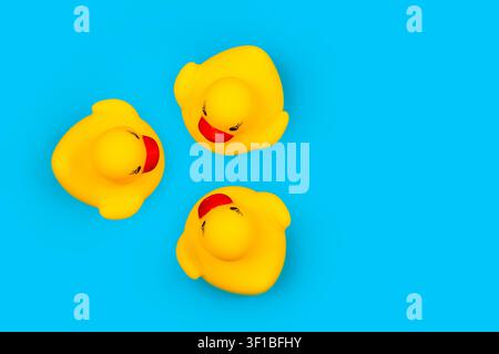 Rubber toy ducklings on a blue background. Three ducklings look at each other. Stock Photo