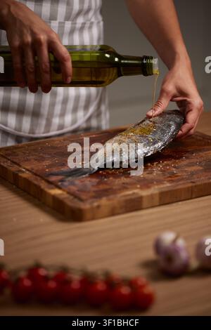 Chef pouring olive oil on fresh fish Stock Photo