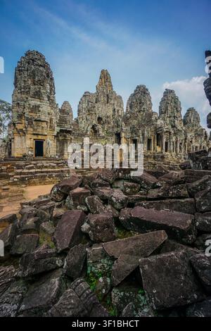 A wide-angle shot shows numerous dark gray and brownish-gray stone blocks scattered in the foreground, some covered with light green moss. Behind thes Stock Photo