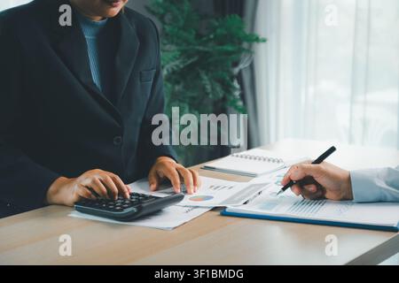 Business professionals reviewing financial reports with calculator, charts and documents on office desk, showing accounting, budget planning, audit an Stock Photo