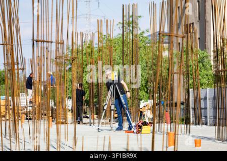 Bucharest, Romania - May 10, 2026: Land surveyor working with total station theodolite on construction site with reinforced steel rebar rods Stock Photo