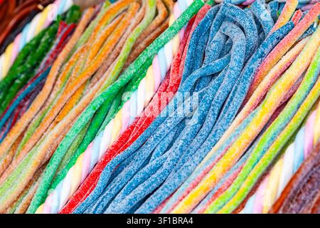 Full frame texture of colorful long gummy candy strips dusted with sugar and twisted marshmallow laces at a confectionery shop Stock Photo