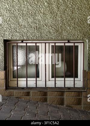 Germany 2026 Close-up of barred window with rusted metal bars and cloudy glass set into textured concrete wall, with window, barred, security, metal d Stock Photo