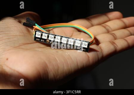 Rigid addressable LED strip or WS2812B 8 bit bar with soldered jumper cables held in the hand Stock Photo