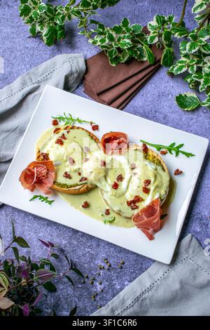 Classic Eggs Benedict with hollandaise sauce and prosciutto, gourmet brunch served on a white plate Stock Photo