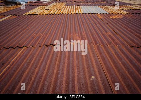 Numerous overlapping corrugated metal sheets, heavily rusted with dark brown, orange, and reddish-brown tones, extend across the frame. Some lighter, Stock Photo