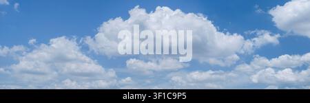 A beautiful horizontal panoramic shot of bright blue skies filled with soft white clouds, ideal for banners and website headers Stock Photo
