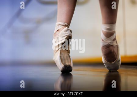 Dancer practices ballet in a bright studio wearing pointe shoes with a focus on footwork and technique during an afternoon session Stock Photo