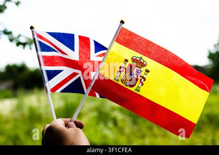 Union Jack and franch tricolor wave together in a verdant park carried by a hand to represent dialogue education abroad cultural exchange and peaceful Stock Photo