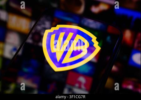 Paris, France - July 12, 2026: The iconic Warner Bros shield logo glowing on a mobile phone screen. Stock Photo