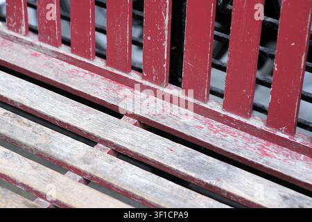 Weathered red wooden bench showing peeling paint and aged texture, creating an abstract background for concepts of time, decay, or vintage outdoor fur Stock Photo