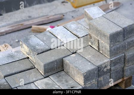 Concrete pavers are neatly stacked on a wooden pallet, organized and prepared for use in a building or landscaping construction project, representing Stock Photo