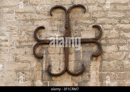 Ornate forged iron anchor plate securing a historical stone masonry wall in Beaune, France Stock Photo