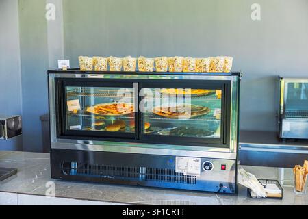 Close-up view of self service food display case with pizza, burgers and popcorn in hotel snack bar. Greece, Crete. Stock Photo