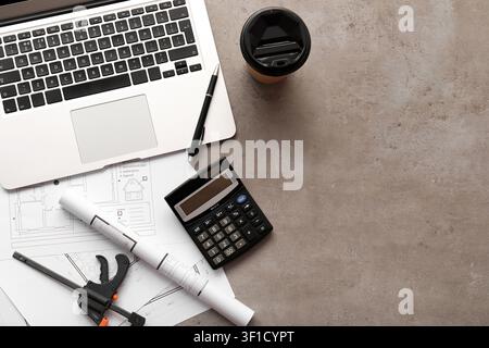 Architectural blueprints and construction tools with laptop, calculator, and coffee on a concrete background Stock Photo