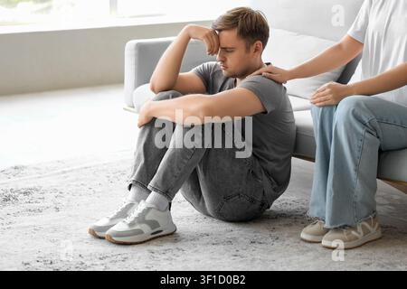 Young woman supporting man with suicidal thoughts at home Stock Photo