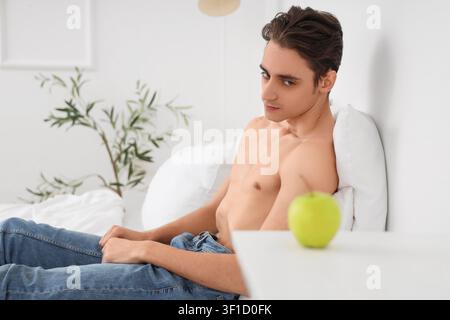 Young man with anorexia refusing from food in bedroom Stock Photo