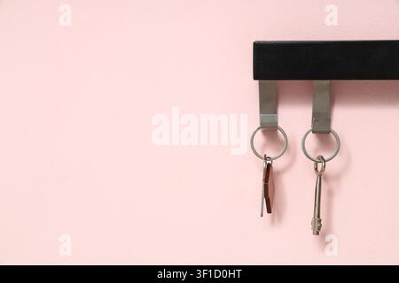 Rack with keys from house on pink wall, closeup Stock Photo