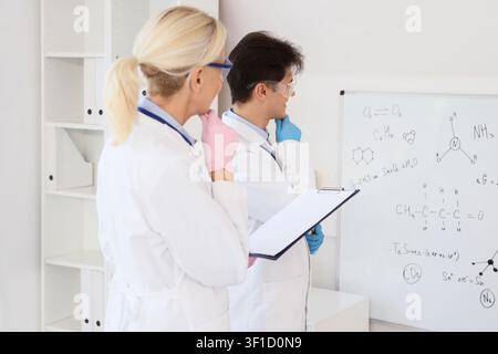 Thoughtful chemists with clipboard working in laboratory Stock Photo