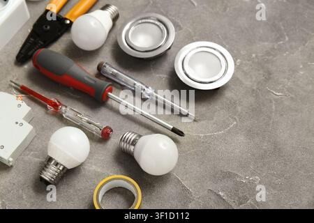 Set of electricians tools, light bulbs and sockets on grey grunge background Stock Photo