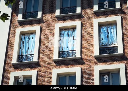 Paris, France. 12th July, 2026. Residents of a Parisian brick apartment building improvise heat shields by taping aluminium survival blankets across their windows in an attempt to block out the scorching sun during an extreme heatwave hitting the French capital. PARIS, FRANCE - JULY 12 2026 - Jacques Julien/Ģ����ý Live News Stock Photo