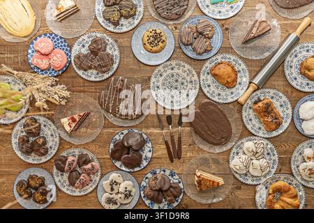 Abundant overhead display of assorted baked goods including chocolate-covered cakes, pink frosted cookies, layered cake slices, and pastries arranged Stock Photo