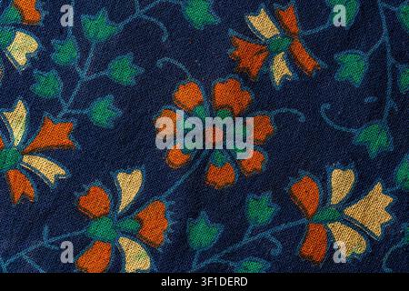 Vintage floral pattern on dark blue fabric texture. Macro shot dark blue textile background with floral ornaments in orange beige and green colors rep Stock Photo