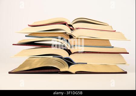 Hardback books opened to the center and stacked neatly on top of one another Stock Photo